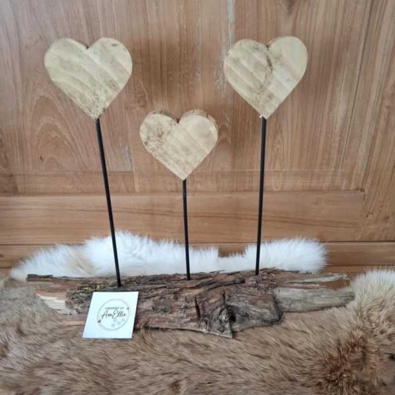 3 hartjes uit grenenhout behandeld met bijenwas op zwart metalen staafje op een basis van schors